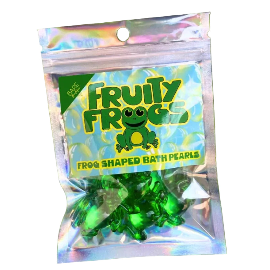 A small resealable pouch labeled 'Fruity Frogs' containing green frog-shaped bath pearls, placed on large water lily pads in water.