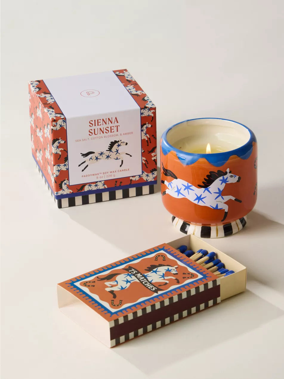 Candle with decorative packaging and matches on a white surface