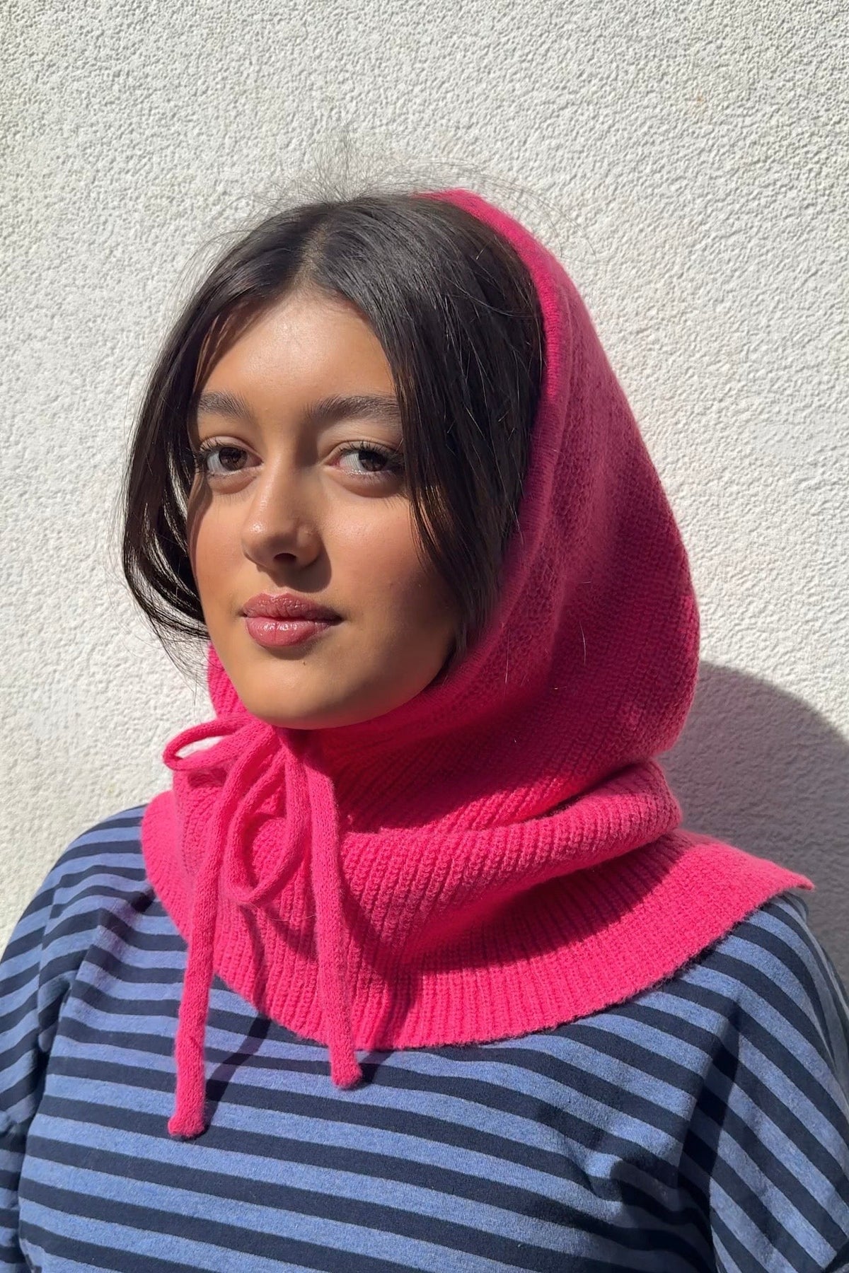 Fuchsia pink knitted balaclava worn as a hood