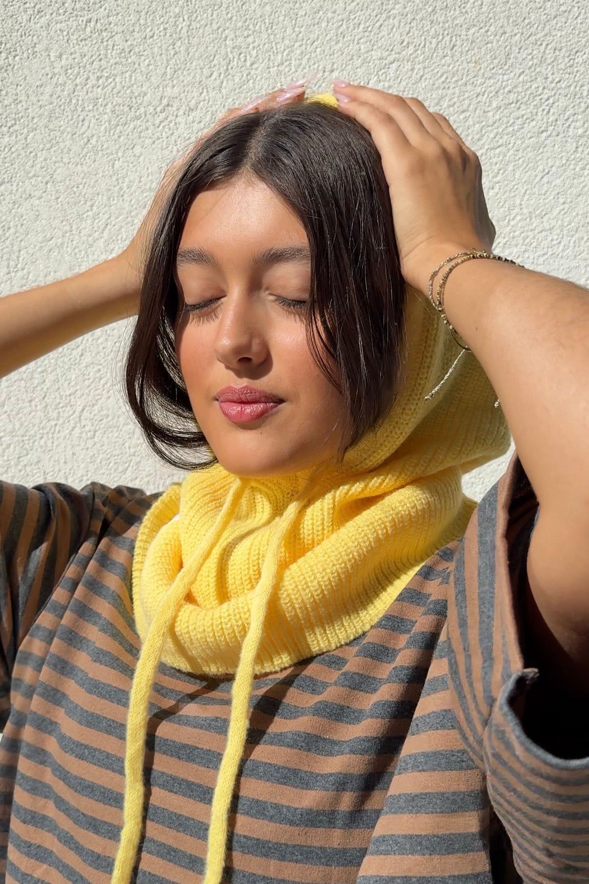 Butter yellow knitted balaclava worn as a hood