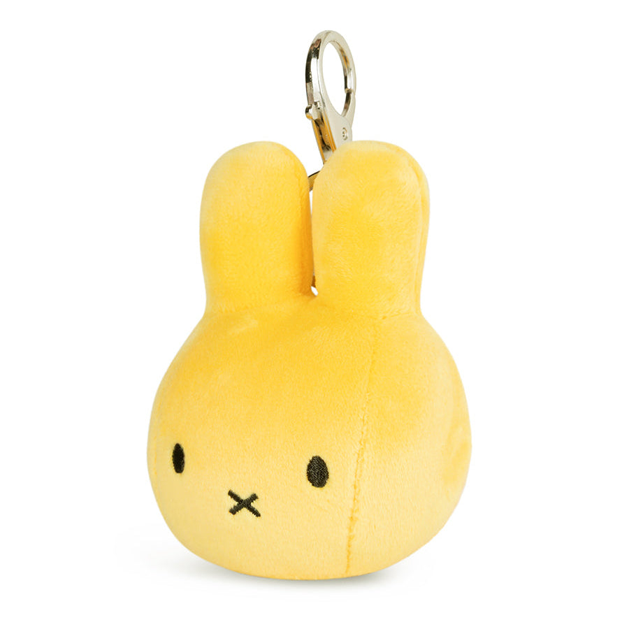 A yellow plush bunny keychain with a silver metal clasp, featuring a simple black embroidered face on a white background.