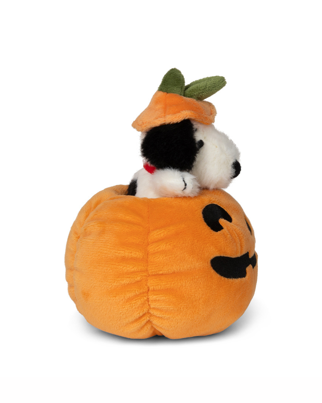 A plush snoopy dog toy sitting inside an orange pumpkin-shaped bed with a carved face, wearing an orange hat with green leaves, on a white background.