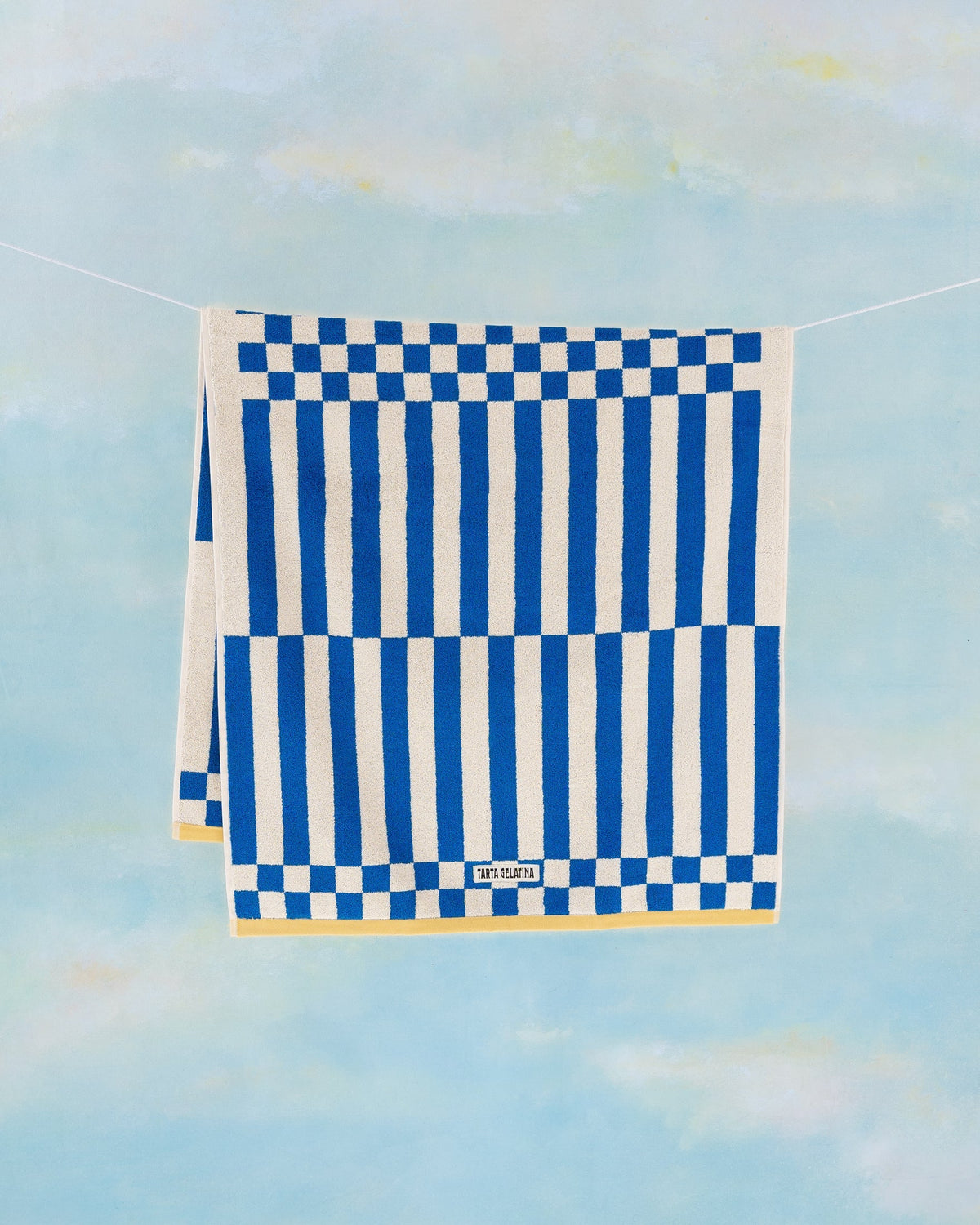 Clubhouse bath towel in blue by Tarta Gelatina, hanging full length