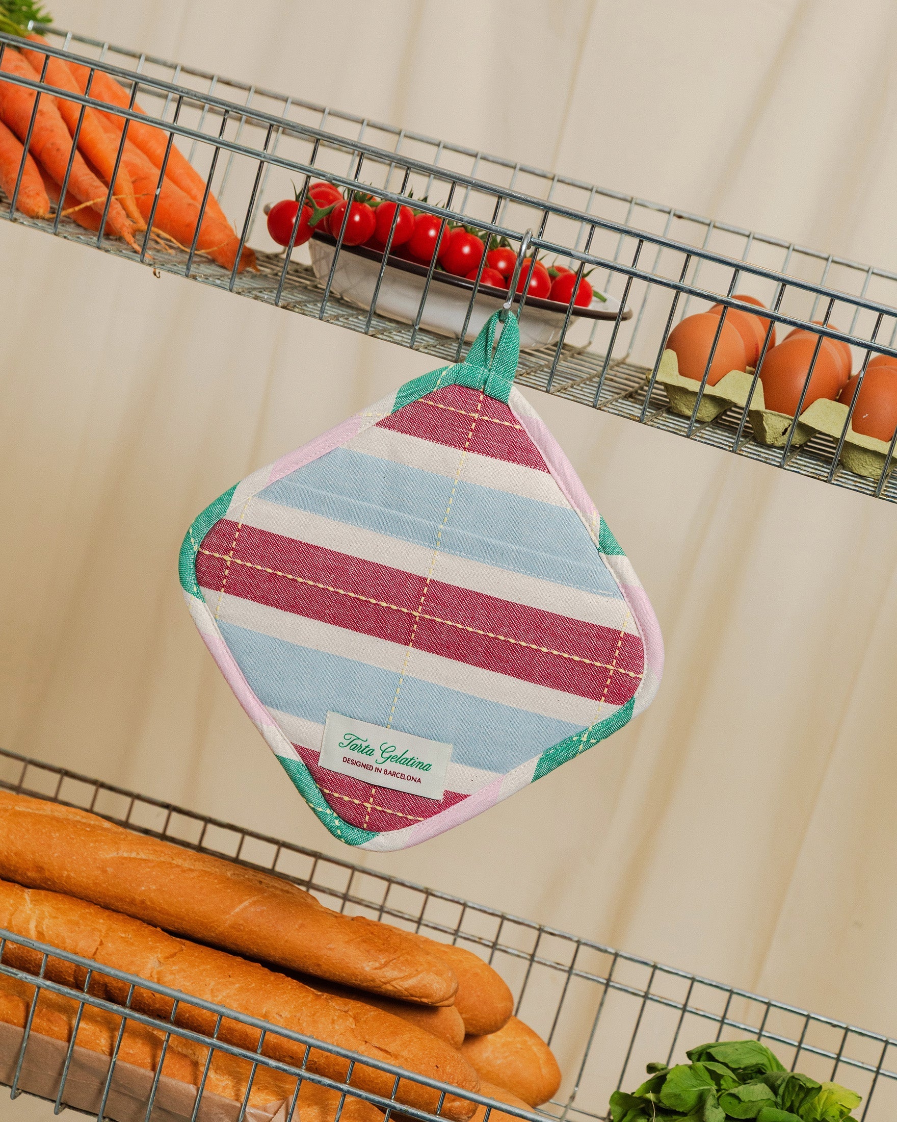 Striped square pot holder by Tarta Gelatina, hanging on kitchen wall