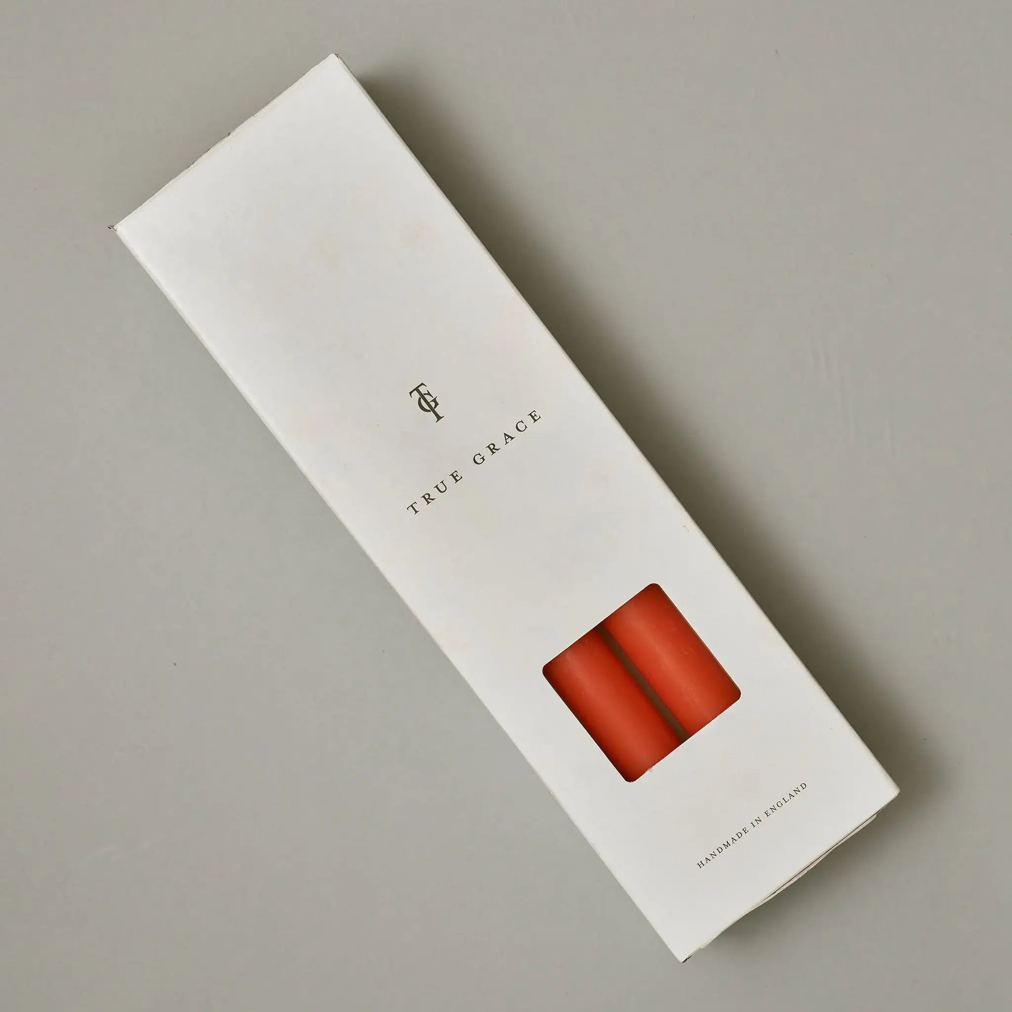 True Grace tangerine dinner candle shown lit