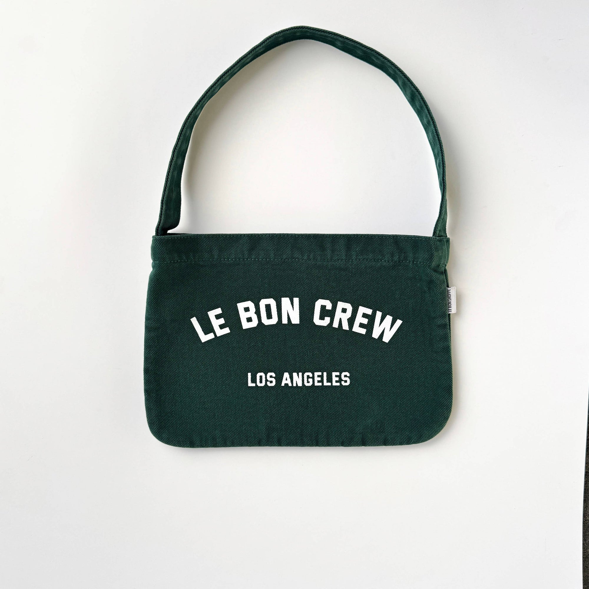 Green handbag with 'Le Bon Crew Los Angeles' text on a white background